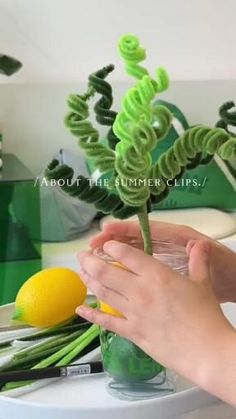 a person holding a lemon in front of a fake plant