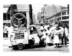 an old black and white photo of people standing in front of a doughnut truck