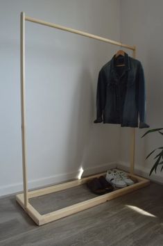 a clothes rack with shoes and jacket hanging on it next to a potted plant