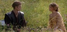 a man and woman sitting on the ground in tall grass, with one looking at the other