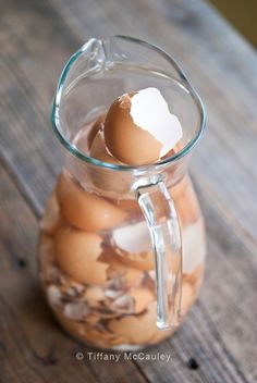 a glass pitcher filled with eggs on top of a wooden table