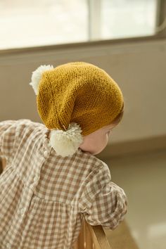 a small child wearing a yellow knitted hat