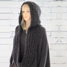 a female mannequin wearing a black sweater and scarf with hoodie on her head