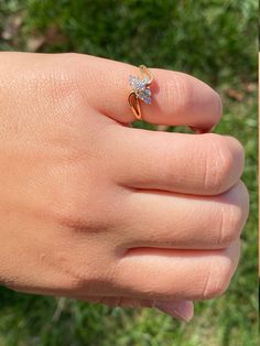 a person's hand with a ring on it and grass in the back ground