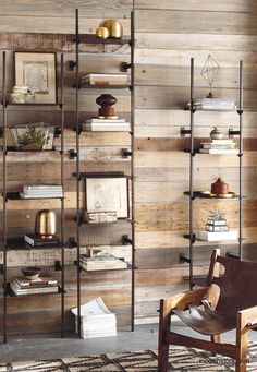 a chair sitting in front of a wooden wall with bookshelves and pictures on it