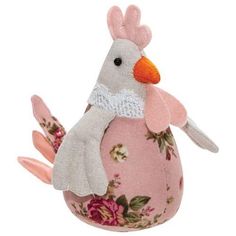 a stuffed bird sitting on top of a pink egg with floral print and white wings