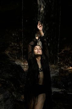 a woman standing in the water with her hands up to her head and arms outstretched