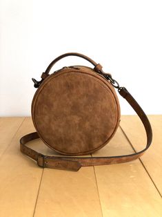 "This crossbody bag is made of high quality vegan leather in brown. It has a circular shape. It is lightweight but durable. It has a rustic, distressed look. It has an adjustable and detachable long strap and a top handle. It is unlined. It can be used as crossbody or clutch. You can see the color options in the last photo. Measurements: Height: 7\" - 18 cm Depth: 3.2\" - 8 cm Detachable strap length: Max 48\" - 124 cm IMPORTANT! Your orders between 7-25 August will be shipped on August 28. Deli Leather Circle Bag, Circle Bag, Brown Backpacks, Brown Tote, Convertible Bags, Round Bag, August 28, Boho Bag, Brown Bags