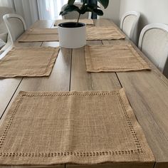 a wooden table with place mats on it and a potted plant in the middle