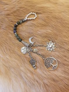 a close up of a bracelet with charms on it and a sun, moon, and fish charm