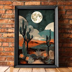 the desert with cactus trees and full moon is shown in a black frame on a brick wall