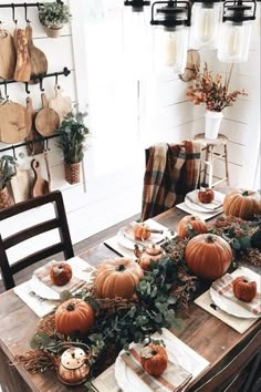 a wooden table topped with lots of pumpkins and greenery on top of it