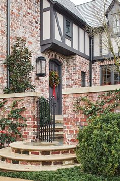 a brick house with steps leading up to the front door and entryway, surrounded by shrubbery