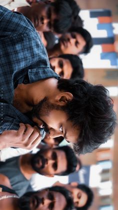 a group of men standing next to each other looking at their cell phones and smiling