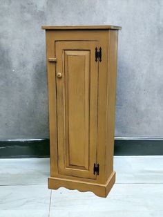 a small wooden cabinet sitting on top of a white tile floor next to a wall