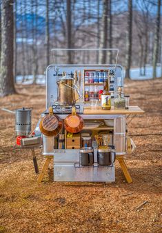 an outdoor cooking station with pots and pans on it in the middle of a wooded area