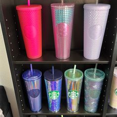 there are many different colored cups on the shelf in this room, and one has a straw