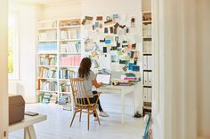 a woman sitting at a desk in front of a book shelf with books on it