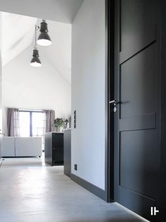 an open door leading into a white room with black doors and lights hanging from the ceiling