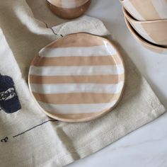 a striped plate sitting on top of a table next to two cups and saucers