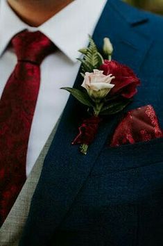 a man in a suit with a red tie and flower boutonniere on his lapel