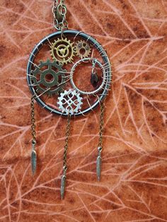 "Combine the worlds of steampunk and fantasy with our handmade steampunk dreamcatcher! This particular model is 100% handcrafted with copper wire, brass chains and gears, a beautiful hanging charm, and unique feather charms dangling off of the bottom.  Our handmade steampunk products are excellent for gifting to anyone who enjoys the steampunk aesthetic or the whimsical nature of dreamcatchers. They will look absolutely spectacular hanging in your bedroom, office, kitchen, living room, or even in your car! They can even make a fine addition to a steampunk costume to make you stand apart from the crowd.  Item Details:  - 2\" metal ring embellished with small gears, copper wire, and unique metal charms   - 1\" inner ring with a moving clock centerpiece  - 3\" metal chain attached to the top Steampunk Metal Necklace For Festivals, Steampunk Metal Necklaces For Festivals, Handmade Steampunk Copper Jewelry, Handmade Steampunk Jewelry For Festivals, Handmade Copper Steampunk Jewelry, Handmade Brown Steampunk Jewelry, Steampunk Dreamcatcher, Steampunk Room Decor, Steampunk Rooms