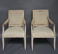 a pair of chairs sitting next to each other on a gray background with white trim