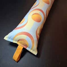 an orange and blue pillow with a wooden handle