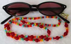 Always keep your reading glasses nearby - use this red/multicolor beaded eyeglass chain! 25.5" in length, made with glass beads, beading cord, metal lobster clasps, and adjustable rubber holders. Lobster clasps make it easy to change the rubber holders, and an extra pair of holders included with every purchase. This bold red/multicolor beaded eyeglass chain will arrive in a gift box, ready to give as a present or to keep and store. Back to Beaded Eyeglass Chains Beaded Eyeglass Chain, Handmade Eyewear, Eyeglass Chains, Beading Cord, Eyeglass Chain, Eyewear Accessories, Reading Glasses, Colored Glass, Beaded Jewelry