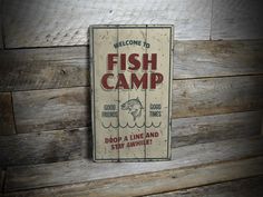 a sign that is on the side of a wooden wall saying, fish camp drop a line and stay awhile