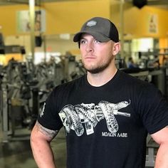 a man in a black shirt and hat standing next to a gym equipment area with machines