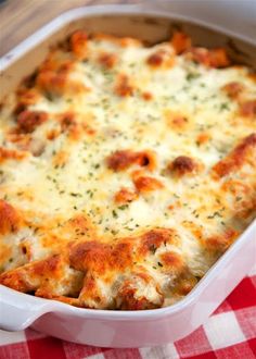 a casserole dish with cheese and meat in it on a checkered table cloth