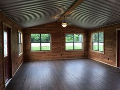 an empty room with wood paneling and windows