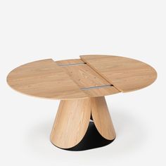 a wooden table with two black legs and an oval shaped plate on the top, sitting in front of a white background