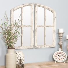 an old white window frame on a mantle with candles and vases next to it