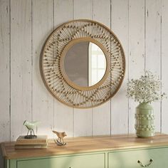 a green dresser with a mirror above it and a small vase on top of it