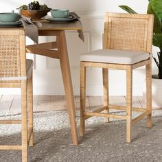 a wooden table with two chairs and a bowl on top of it next to a potted plant