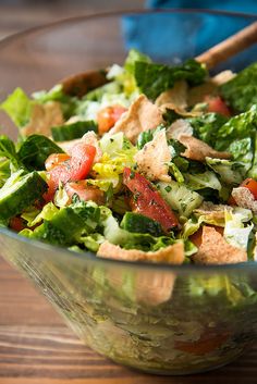 a salad with lettuce, tomatoes and tortilla chips in a glass bowl