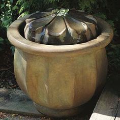 a large potted planter sitting on top of a cement slab next to a wooden bench