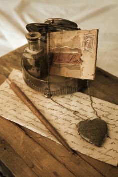 an old letter, inkwell and other items sit on top of a wooden box