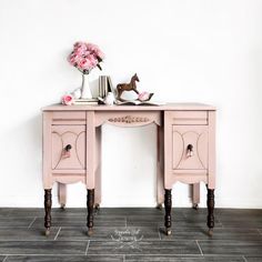 a pink desk with two drawers and flowers on top