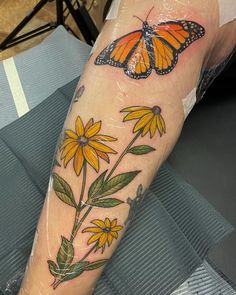 a woman's arm with a butterfly and flowers on it