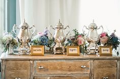 an old dresser is adorned with trophies and vases for wedding guests to sign on