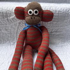 a sock monkey with big eyes sitting on a bed