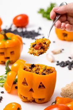 someone is holding a spoon with some food inside of pumpkin - shaped jack - o'- lanterns