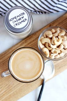 two cups of coffee with cashews next to each other on a cutting board