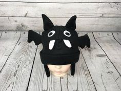 "Baby and Kids Black Bat Fleece Hat This is a bat hat made from black fleece. It features felt eyes, fleece teeth, fleece ears, and fleece wings. Hat Sizes: Baby: Approx. 20\" around Child: Approx. 22\" around Youth: Approx. 23 1/2\" around Hat shown is a child size on a 18 1/2\" (47cm) head. Care: Machine wash on cool or warm; dry on low. Turnaround time is 1-3 business days. Standard Shipping is usps first class (3-5 business days). Upgrade to priority (2-3 day) and priority express (1-2 day) Black Novelty Hat For Halloween, Black Beanie For Halloween, Black Felt Hat For Halloween Costume, Themed Black Costume Hats For Winter, Black Novelty Beanie Hat, Novelty Black Beanie Hat, Themed Black Winter Hats, Black Felt Cap For Winter, Black Winter Felt Hat