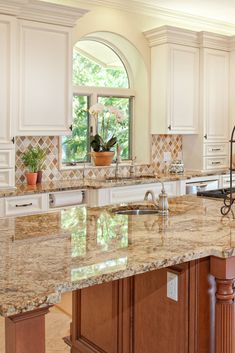 a kitchen with marble counter tops and white cabinets