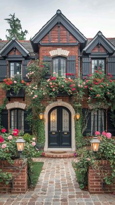 a brick house with lots of flowers growing on it's front door and windows