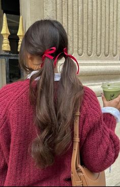 a woman in a red sweater is holding a cup and looking at her cell phone